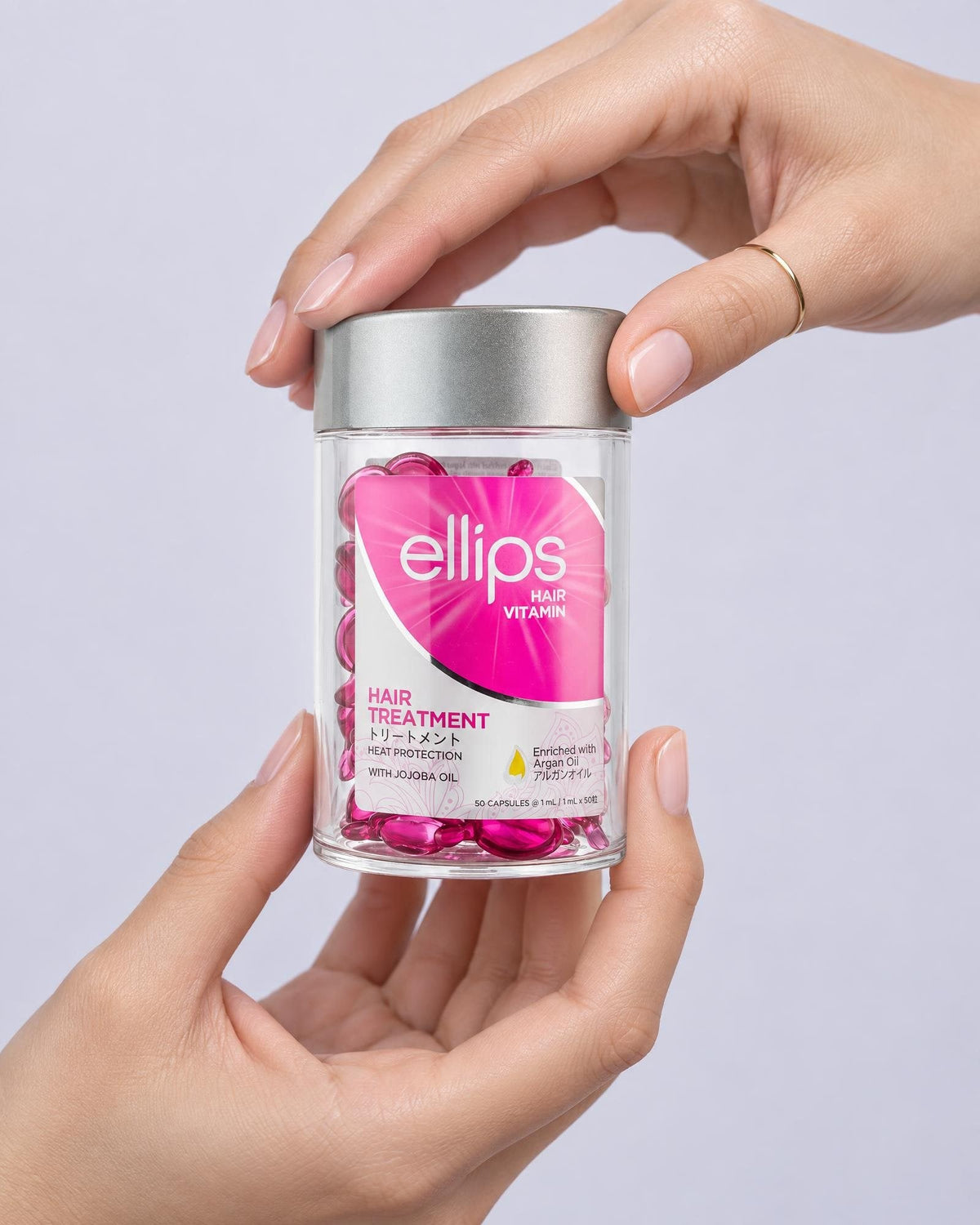 Kaksi kättä pitelee Ellips Hair Treatment -purkkia