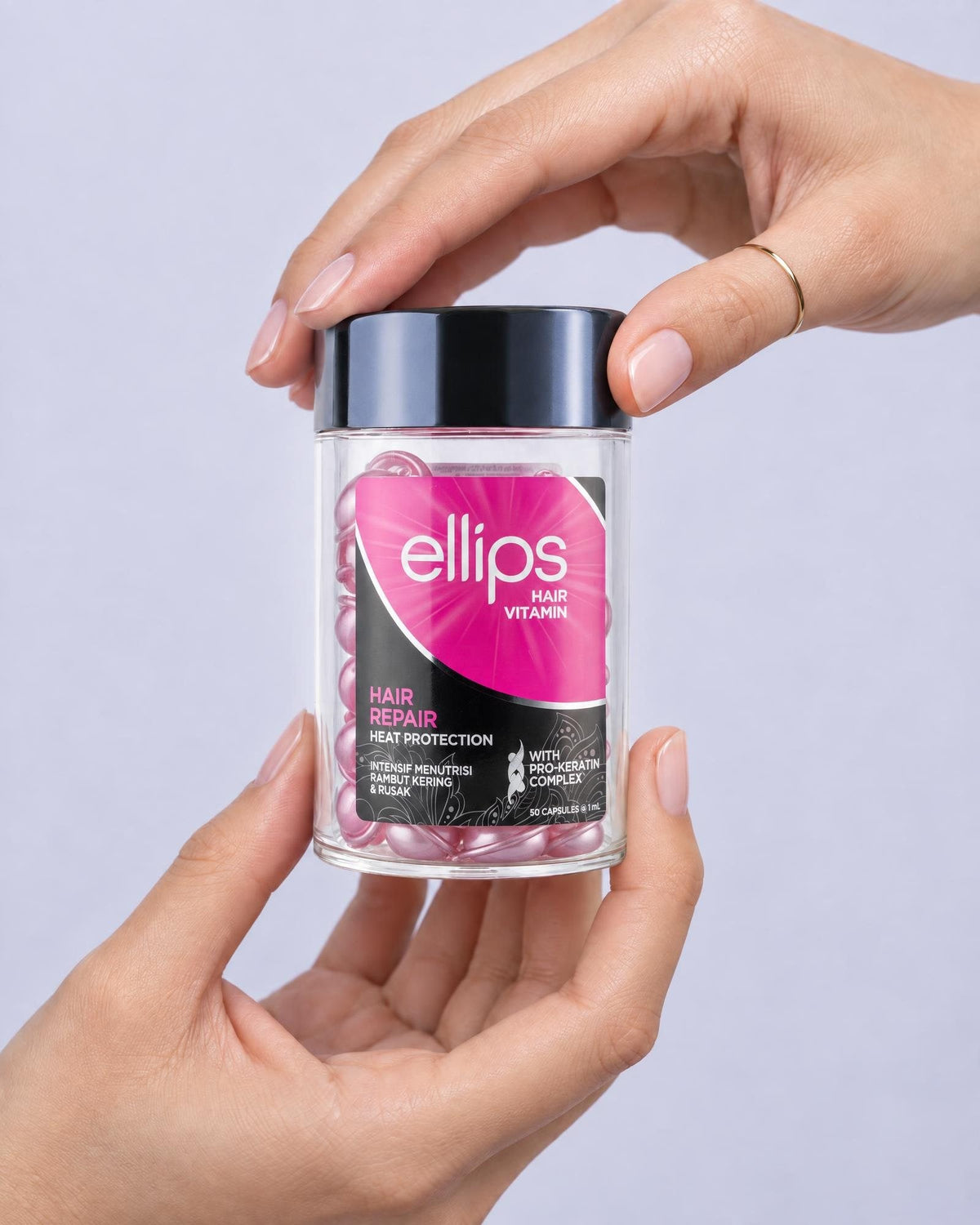Kaksi kättä pitelee Ellips Hair Repair -purkkia