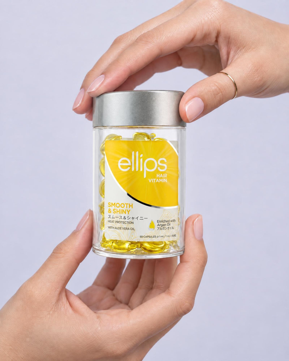 Kaksi kättä pitelee Ellips Smooth & Shiny -purkkia