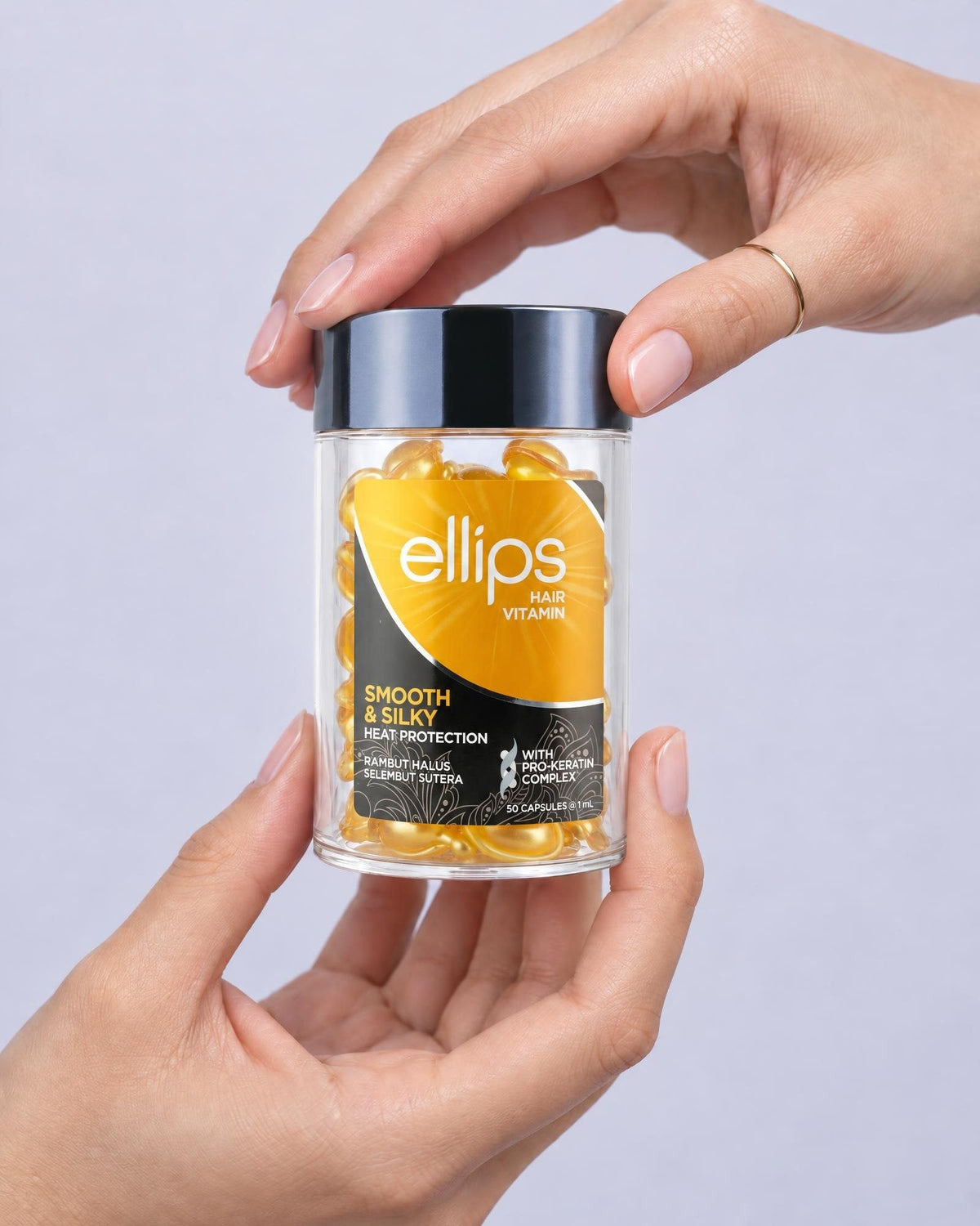 Kaksi kättä pitelee Ellips Smooth & Silky -purkkia